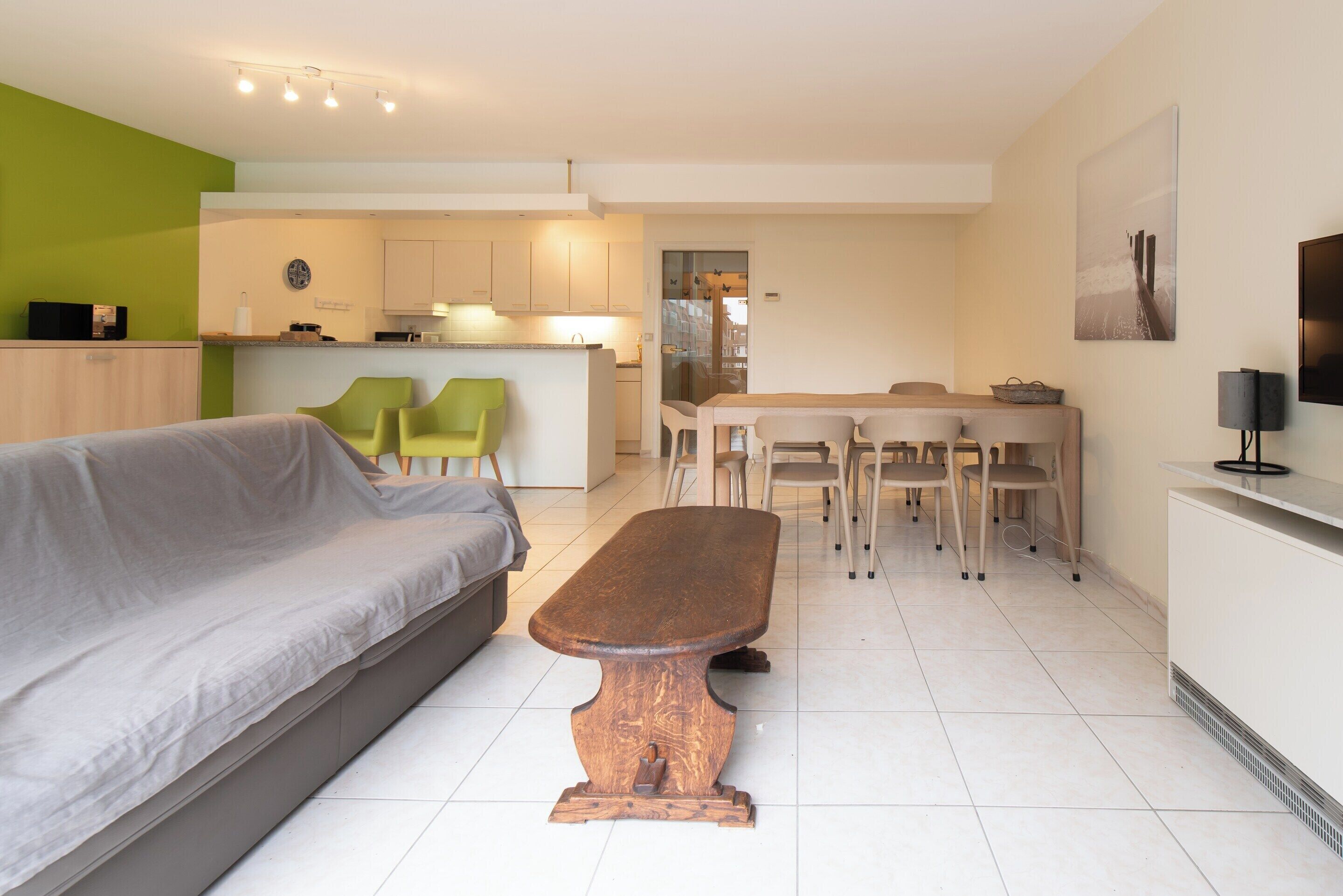 Una sala de estar moderna con un sofá, una mesa de centro de madera y un comedor con sillas y una mesa.