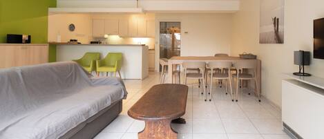 Una sala de estar moderna con un sofá, una mesa de centro de madera y un comedor con sillas y una mesa.