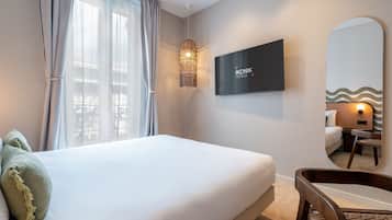 Una habitación de hotel con una cama, un televisor montado en la pared y un espejo grande.