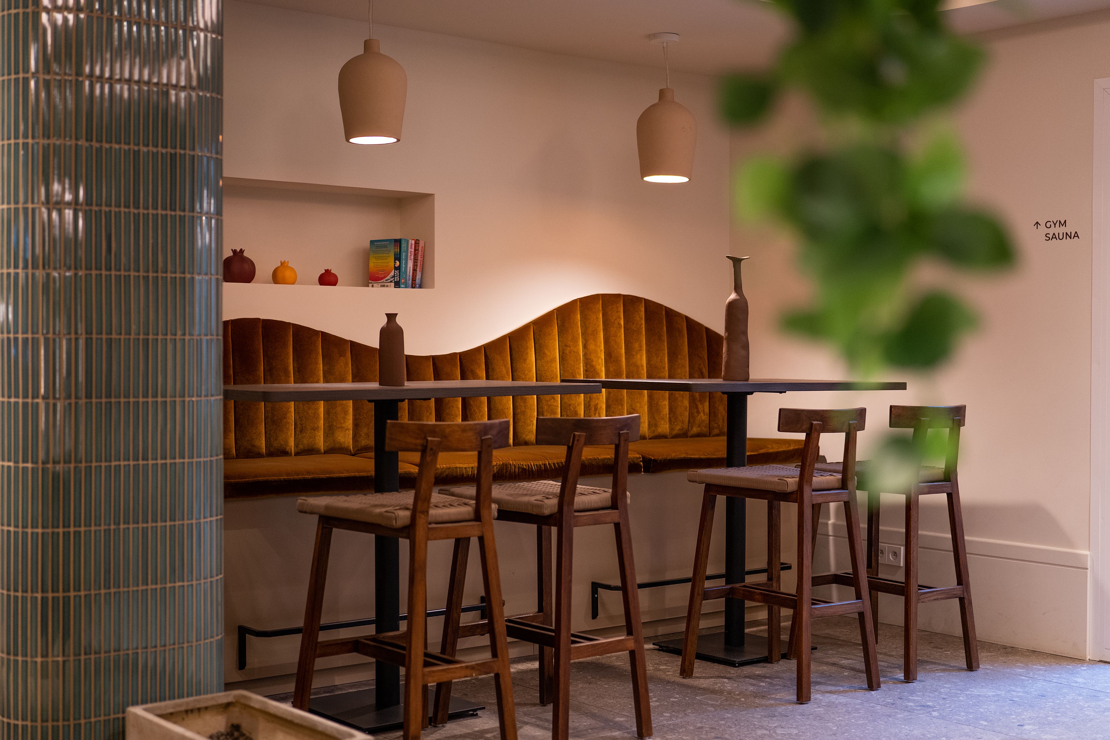 Eine Bar mit Holzsesseln, einer Bar, hängenden Lampen und einem an der Wand befestigten Regal mit Büchern und Dekoration.