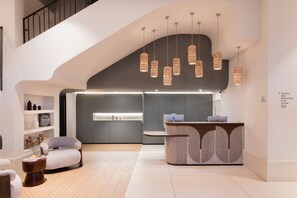 Eine moderne Hotelhalle mit einer Rezeption, einer Sitzecke und einer Treppe.