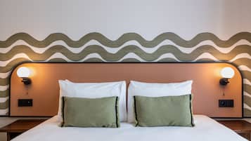 Una cama con dos almohadas, cabecera con diseño ondulado e iluminación en la pared.