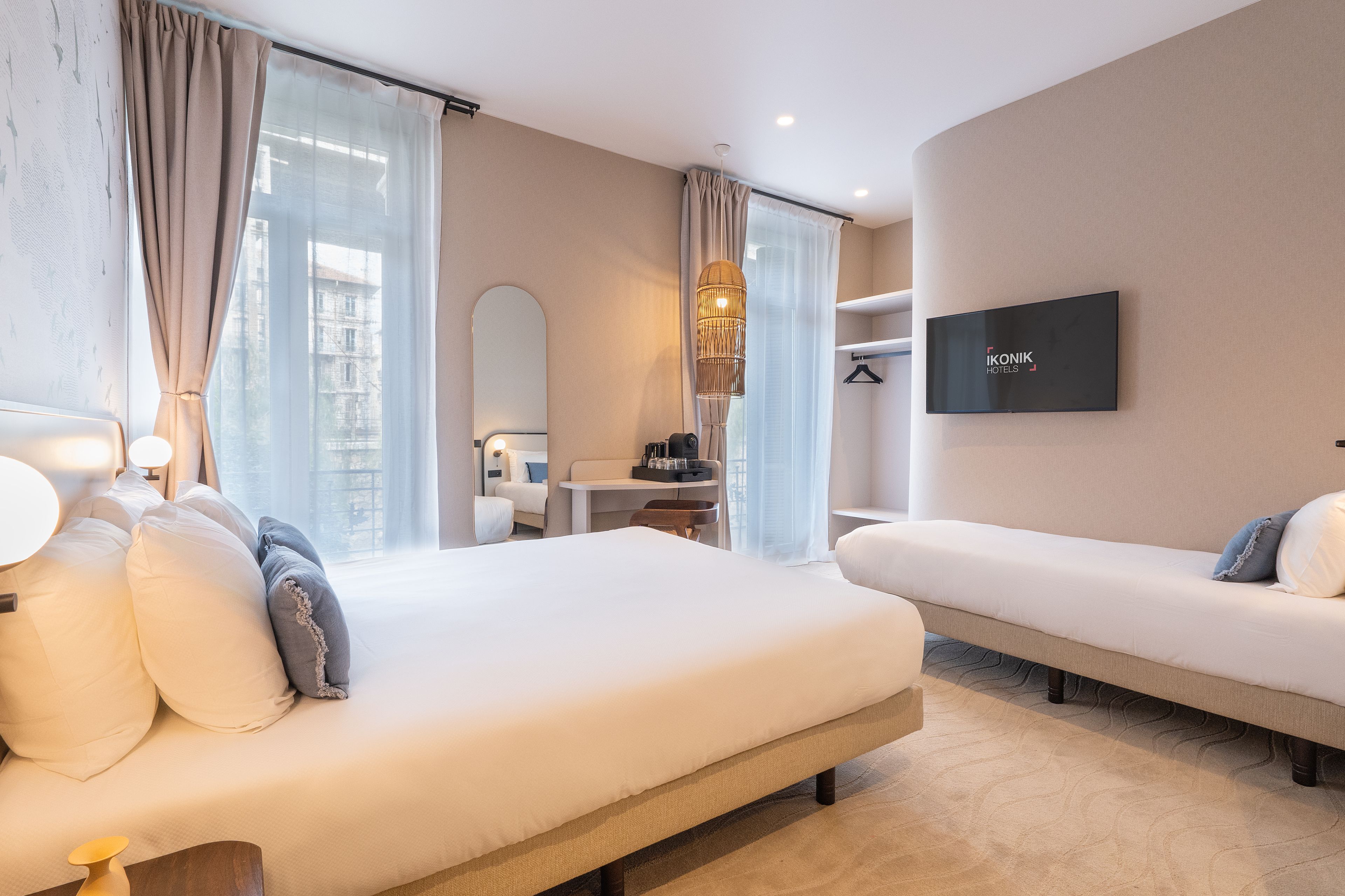 Een hotelkamer met een bed, nachtkastje, lamp, televisie en uitzicht.