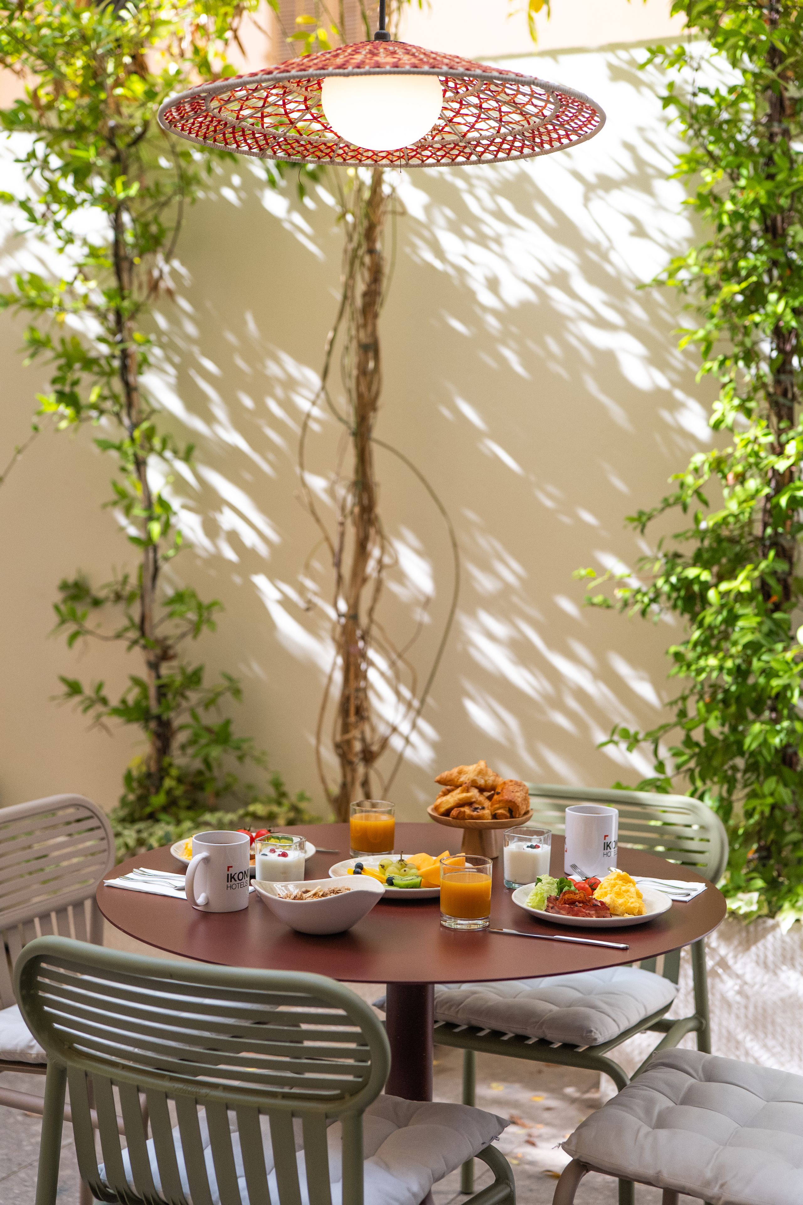 An outdoor dining area with a round table, chairs, and a hanging light fixture.