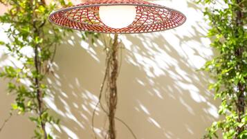 An outdoor dining area with a round table, chairs, and a hanging light fixture.