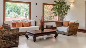 Un salón amplio con un gran ventanal, una mesa de centro y muebles de mimbre.