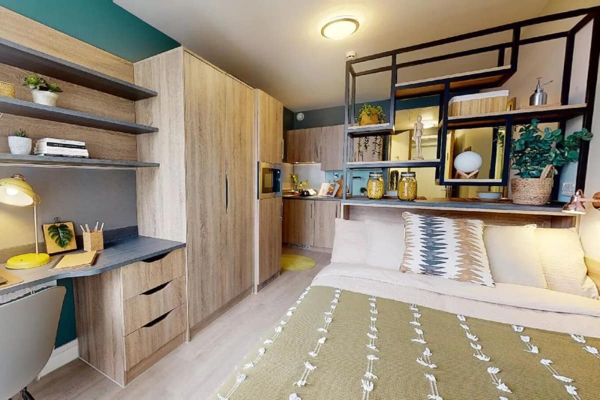 Une chambre à coucher de taille réduite, comprenant un lit, un bureau et des étagères.
