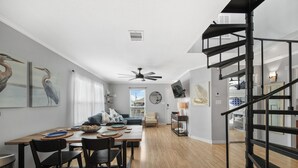 A modern living space with a dining area, a staircase, and a view of the outside. - Twins Tidal Escape, Sweet Memories, S'More Fun (Galveston)