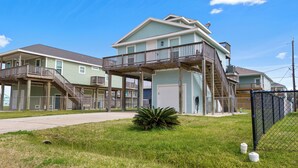 A beachfront property with multiple levels, outdoor staircases, and a fenced area. - Twins Tidal Escape, Sweet Memories, S'More Fun (Galveston)