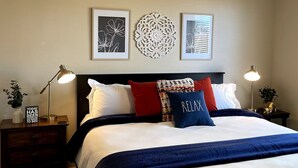 A bedroom with a bed, nightstands, a ceiling fan, and wall art.