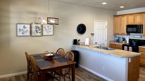 A modern kitchen with wooden cabinets, a black microwave, and a sink.