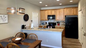 A modern kitchen with wooden cabinets, a black refrigerator, a microwave, and a stove.