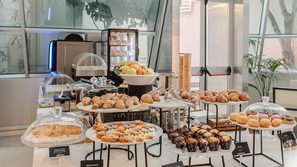 Un buffet proposant une variété de viennoiseries et de desserts, notamment des gâteaux et des croissants, présentés sur plusieurs présentoirs.