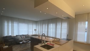 A modern kitchen with a central island, a dining area with a sofa and chairs, and large windows providing natural light.