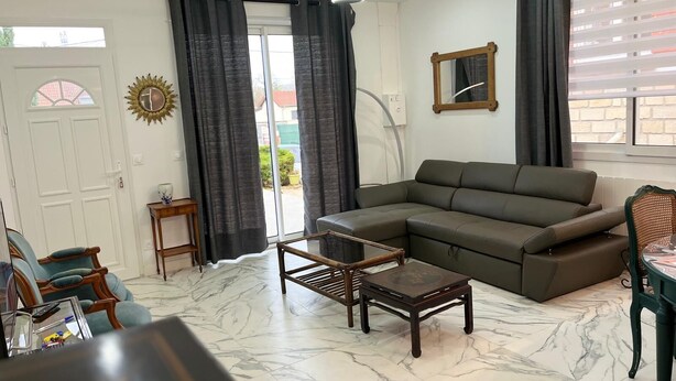 Una sala de estar con un sofá modular, una mesa de centro y una mesa de comedor con sillas.
