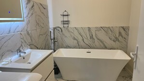 Un baño moderno con una bañera independiente, un tocador con lavabo y un perchero para toallas.