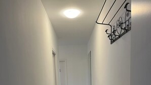 Un pasillo estrecho con paredes blancas y suelo de diseño marmolizado. Un banco está colocado contra la pared a la derecha.