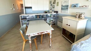 A compact kitchen with a white table, wooden chairs, and a white cabinet. - Cozy One-bedroom Apartment With sea View (Middelkerke)