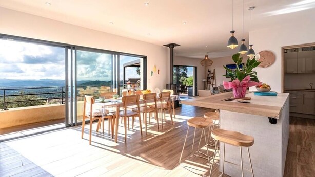 A modern kitchen with a large island, bar stools, and a view of the outdoors. - 150m2 4 bedroom family home located in San gavino 10min from figari (Figari)