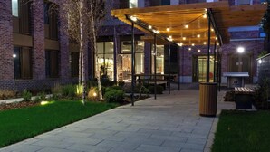 Un bâtiment en briques doté d’un patio couvert, d’un espace extérieur aménagé pour s’asseoir et d’une poubelle.