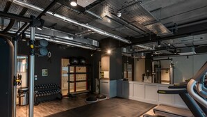 Une salle de sport équipée de matériel de musculation, de tapis de course et dotée d’un mur recouvert de miroirs.