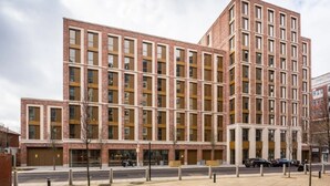 Un immeuble à plusieurs étages, doté d’une façade en briques, de grandes fenêtres et d’un toit plat.