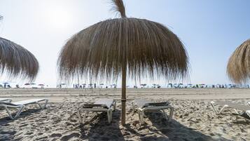A beach with lounge chairs and umbrellas.