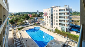 A swimming pool with a view of a modern building and surrounding greenery.
