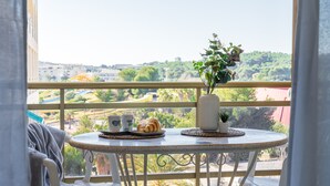 A balcony with a table set for breakfast, including croissants and coffee cups, overlooking a scenic landscape.