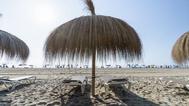 A beach with lounge chairs and umbrellas.