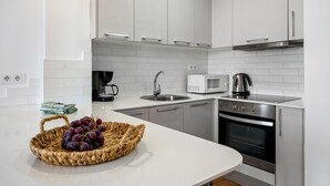 Una cocina moderna con armarios blancos, electrodomésticos de acero inoxidable y encimera blanca.