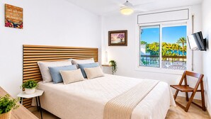 Un dormitorio con cama, televisión, ventana con vistas y una planta.