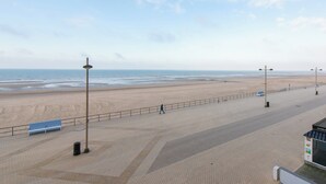 A beachside promenade with a bench, street lamps, and a clear view of the ocean. - Apartment in Middelkerke With Sea View (Middelkerke)