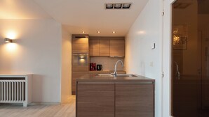 A modern kitchen with wooden cabinets, a built-in oven, and a sink. - Apartment in Middelkerke With Sea View (Middelkerke)