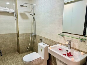 Un baño con inodoro, ducha y lavamanos con velas.