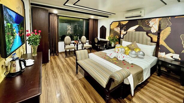 A hotel room with a large bed, a TV, a desk, and a chair. - Bao Anh Hotel (Hanoi)
