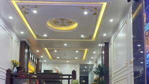A grand staircase with a marble finish, leading to a reception area with a counter and potted plants. - Bao Anh Hotel (Hanoi)