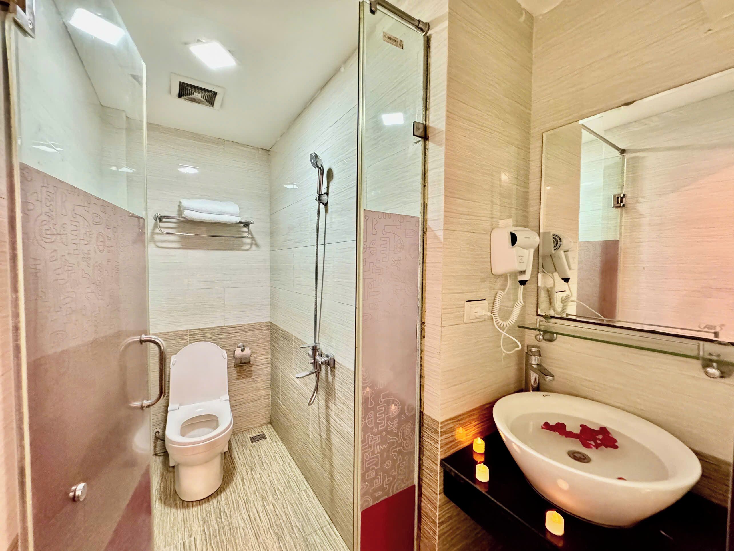 Un baño moderno con cabina de ducha de vidrio, inodoro, lavabo con espejo y toallero.