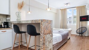 A modern room with a bed, a desk with two chairs, a TV, and a window with curtains. - Monastiraki 507 Superhost Hub (Athens)