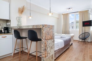 Una habitación moderna con cama, escritorio con dos sillas, televisor y ventana con cortinas.