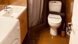 Ein kleines Badezimmer mit einem weißen Waschbecken, einer Toilette und einer Duschvorhang.