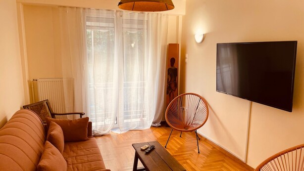 Ein modernes Wohnzimmer mit einer Couch, einem Couchtisch, einem Fernseher und zwei Sesseln.