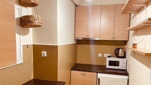 Eine kleine Küche mit Holzausstattung, einer Mikrowelle und einer Kaffeemaschine auf der Arbeitsfläche.