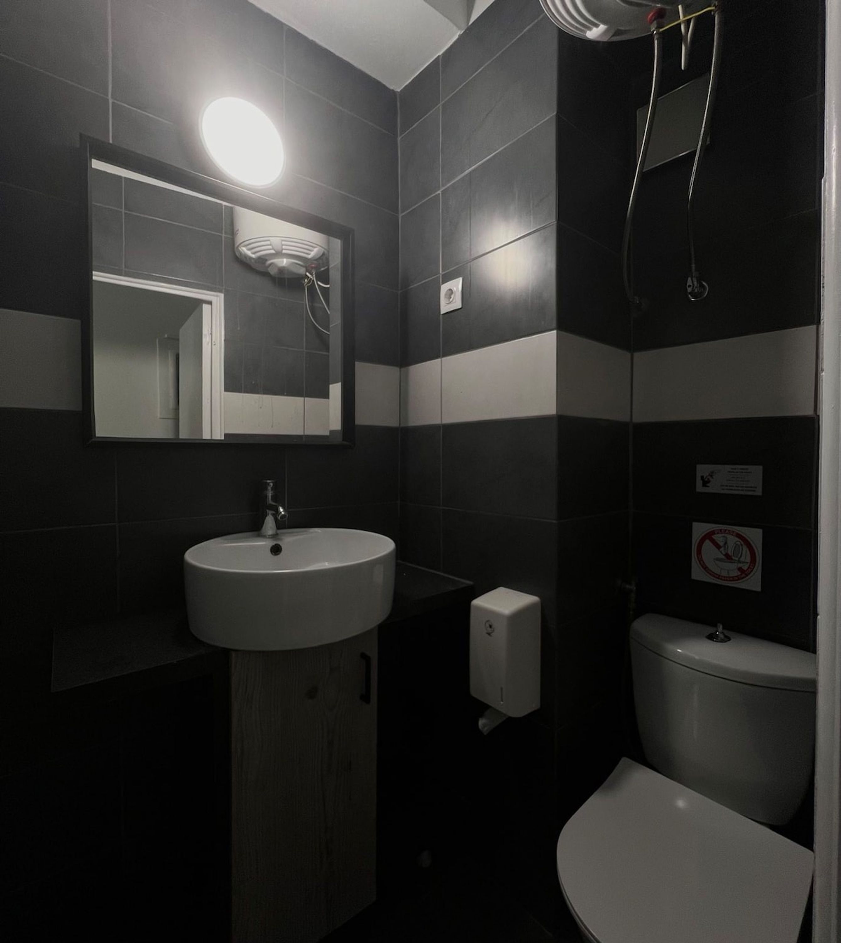 Un baño con lavamanos blanco, un espejo, inodoro y ducha.