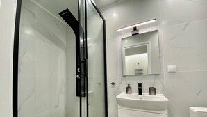 A modern bathroom with a glass-enclosed shower, a white sink with two bottles, and a mirror above the sink. - 305 Monastiraki 305 Superhost Hub (Athens)