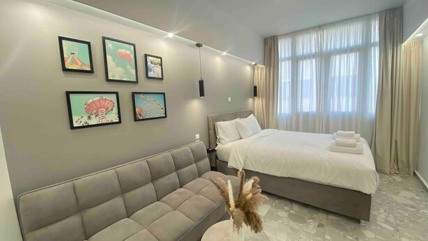 A modern bedroom with a large bed, a sofa, and wall-mounted artwork. - 305 Monastiraki 305 Superhost Hub (Athens)