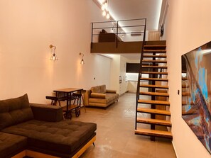 Um espaço de estar moderno estilo loft, com beliche, área de refeições e escada.