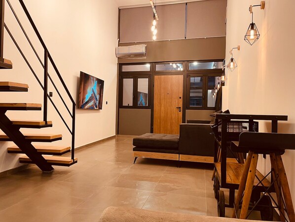 Um interior moderno com uma escada, um sofá, uma mesa de jantar e uma pintura.