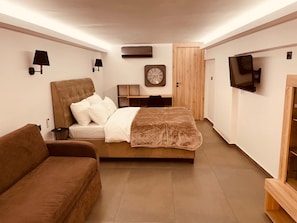 Um quarto moderno com uma cama grande, um sofá, uma TV e um relógio na parede.