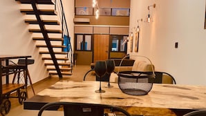 Un comedor moderno con una mesa de madera, sillas negras y una escalera.